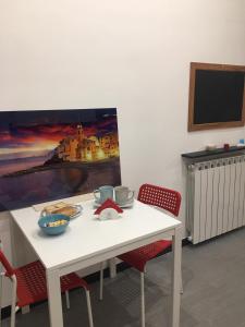 a white table with red chairs and a tv on a wall at Triglia in Genoa