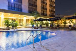 uma piscina num hotel com cadeiras e guarda-sóis em Movich Hotel de Pereira em Pereira