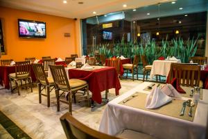 a restaurant with tables and chairs and a tv at Hotel Buenos Aires in Cartagena de Indias