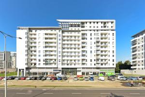 a large white building with cars parked in a parking lot at Aviator Modern 83 in Gdańsk