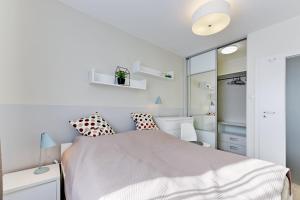 a white bedroom with a bed and a mirror at Aviator Modern 83 in Gdańsk