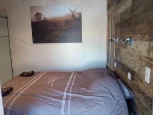 a bed in a bedroom with a picture on the wall at L'Etable d'Evelyne in Bastogne