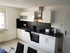 a kitchen with white cabinets and a black counter top at Lüdenscheid-Ferienwohnung de Betzler Weh29-100 in Lüdenscheid