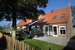 a house with an orange roof and a fence at Vakantiehuizen 't Centrum in Oostkapelle