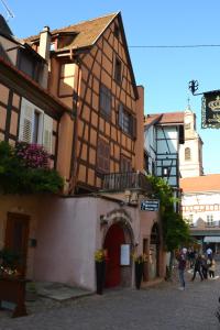 un bâtiment dans une rue où les gens passent à pied dans l'établissement P'tit Biscuit, à Riquewihr