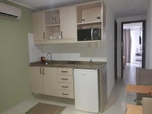 cocina con armarios blancos y microondas en Flat à beira mar en João Pessoa