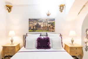 Schlafzimmer mit einem Bett mit weißer Bettwäsche und lila Kissen in der Unterkunft M Empire in Rom