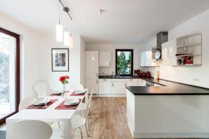 a white kitchen with a table and white chairs at Ferienwohnung Niederschönhausen in Berlin
