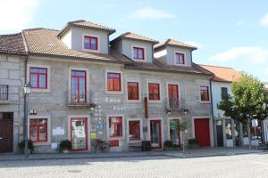 a large stone building with red windows on a street at Casa Fontes in Pedras Salgadas