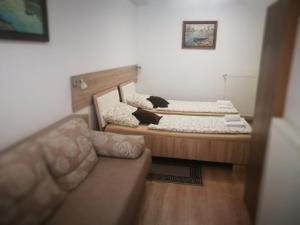 two beds in a small room with a couch at Rooms Aračić in Slavonski Brod