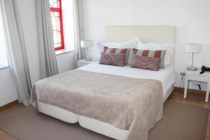 a white bedroom with a large white bed with pillows at Casa Fontes in Pedras Salgadas