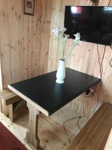 einen schwarzen Tisch mit einer Vase mit weißen Blumen darauf in der Unterkunft Cosy Countryside Log Cabin in Kilkenny