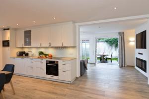 a kitchen with white cabinets and a living room with a table at Strandgut 3 in Westerland