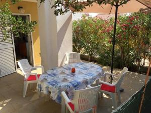 a table with four chairs and an umbrella on a patio at Apartmani Hržan-Keglević in Mandre