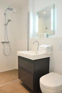 ein Badezimmer mit einem Waschbecken, einem WC und einem Spiegel in der Unterkunft Suite Gartenstraße im hellen Ambiente in Norderney