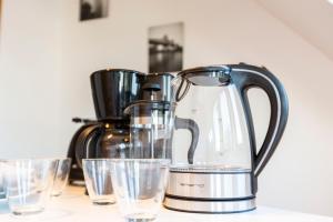 a tea kettle and glasses of water on a counter at AVR Apartment HOF 8 in Bremerhaven