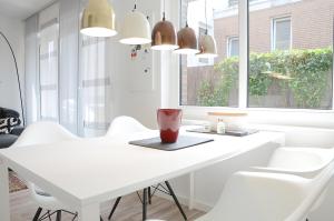 ein weißes Esszimmer mit einem weißen Tisch und weißen Stühlen in der Unterkunft Suite Gartenstraße im hellen Ambiente in Norderney