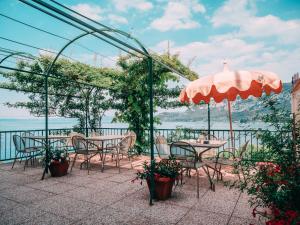 eine Terrasse mit Tischen, Stühlen und einem Sonnenschirm in der Unterkunft Welcome Traveller VILLA ARIGONI in Garda