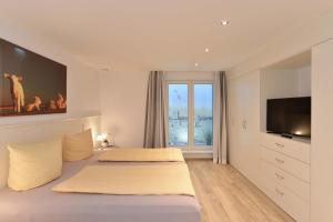 Schlafzimmer mit einem Bett, einem TV und einem Fenster in der Unterkunft Strandgut 3 in Westerland