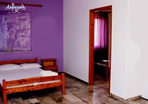 a bedroom with a bed and a purple wall at Akrogiali Hotel Restaurant in Xiropigado