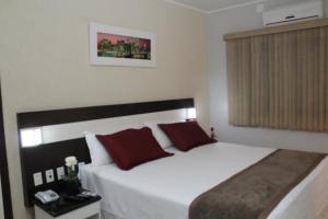1 dormitorio con 1 cama blanca grande con almohadas rojas en Itamaraty Hotel, en Anápolis