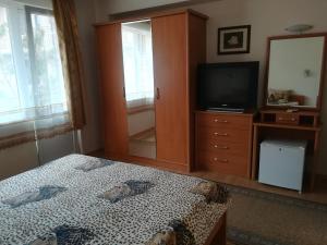 a bedroom with a bed and a dresser with a television at Guest House Georgieva Ravda in Ravda +43 photos