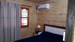 a bedroom with wooden walls and a bed and a window at Posada del Campo in San José