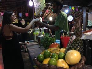 a woman handing a man a drink at a fruit stand at Lagarto Na Banana Hostel in Pipa