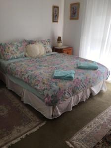a bedroom with a bed with a flowered blanket and a table at La Casa Della Nonna in Australia in Lakes Entrance