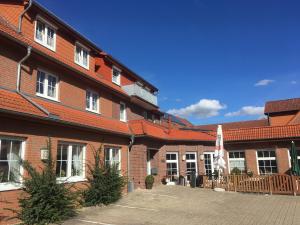 - un bâtiment en briques rouges avec une cour dotée d'un parasol dans l'établissement Gasthof Jörns, à Diekholzen