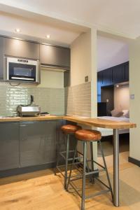 a kitchen with a wooden counter and stools at Forbee Studios in London