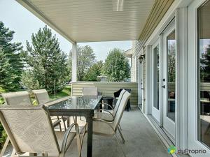 een afgeschermde veranda met een glazen tafel en stoelen bij Condo Le Champlain - 105 in Bromont