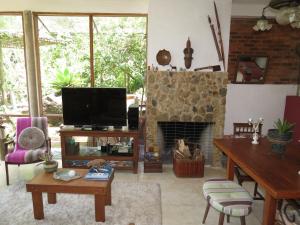 a living room with a tv and a fireplace at Casa de vidro in Petrópolis