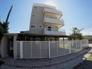una casa con una cerca blanca delante de ella en Costa do Sol Residencial, en Bombinhas