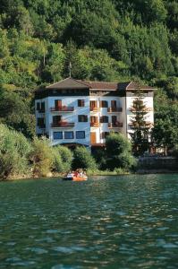 un bâtiment au bord d'une rivière avec un bateau dans l'établissement Hotel Acquevive, à Scanno