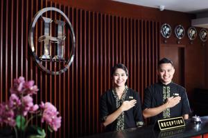 um homem e uma mulher em pé em frente a um espelho em Grand Hatika Hotel em Tanjung Pandan