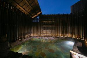 a swimming pool with a wooden fence next to a pool at Yufuin Bath Satoyamasafu in Yufu +38 photos