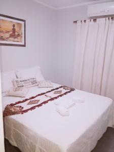 1 dormitorio con cama blanca y cortinas blancas en Casa de Vacaciones ADELITA en 