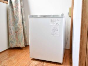 a white refrigerator in a room with a curtain at New Wel City Miyazaki in Miyazaki