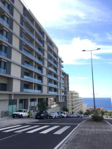 uma rua da cidade com um grande edifício e um parque de estacionamento em Lou-Jos no Funchal