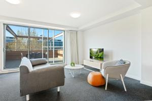 a living room with a couch and chairs and a tv at Quest Newcastle in Newcastle