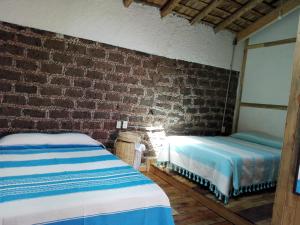 a bedroom with two beds and a brick wall at Casa del siglo XVII in Jocotitlán +40 photos