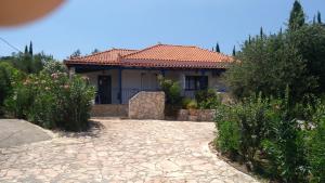 a house with a stone driveway in front of it at Takis Haikos House two minutes walk to the beach Peroulia in Vounaria