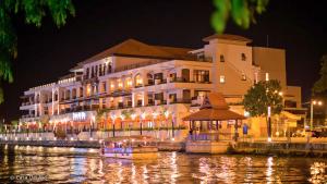 a large building next to a river at night at Cozy Riverside Hotel in Malacca