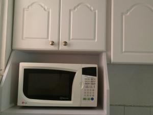 a microwave in a kitchen with white cabinets at Room 4 rent in San Salvador