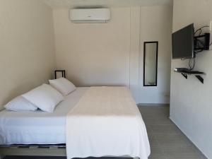 a bedroom with a bed with white sheets and a television at Casa Kay in Playa del Carmen