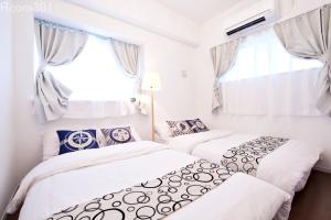 Duas camas num quarto branco com uma janela em La Fonte UK2 em Ginowan