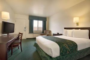 a hotel room with a bed and a desk and a television at Travelodge by Wyndham Winslow in Winslow