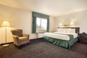 a hotel room with a large bed and a chair at Travelodge by Wyndham Winslow in Winslow