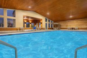 a large pool in a hotel with chairs and tables at AmericInn by Wyndham Boscobel in Boscobel